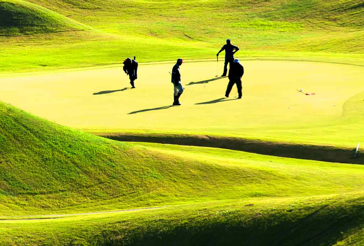 A group of four is playing golf out on the green