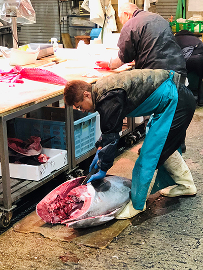 One of the many fish vendors "middlemen" in the Osaka Fish Market. Cutting up the tuna and distributing the prized fish to the sushi restaurants in Osaka.